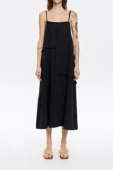 Vestido midi negro de corte recto y tirantes finos, con paneles y detalles desflecados.