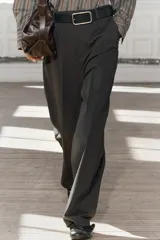Pantalón de tiro medio color verde oscuro, confeccionado en hilatura con viscosa. Cintura con trabillas, bolsillos delanteros, pierna ancha y cierre frontal con cremallera, botón y gancho metálico.