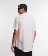 Camisa boxy de hombre confeccionada en viscolino color crudo con rayas texturizadas, cuello inglés, solapa, mangas cortas y abotonado frontal.
