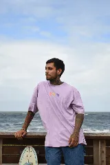 Remera lila de algodón con cuello redondo y mangas cortas. Estampado frontal con diseño de flores y sol en tonos pastel.