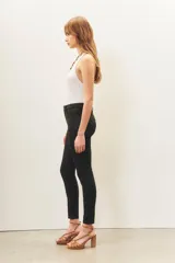 Pantalón de jean negro de corte skinny y tiro alto, confeccionado en gabardina con elastano y recubrimiento que simula cuero.