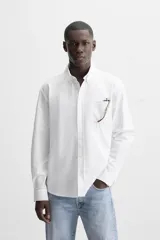 Camisa azul marino de corte regular fit, confeccionada en tejido de algodón Oxford. Tiene cuello abotonado, manga larga con puños abotonados, bolsillo de parche en el pecho y cierre frontal con botones.