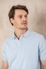 Chomba azul marino de piqué con cuello clásico, tapeta de dos botones y logo de pájaro bordado en color rosa en el pecho.