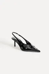 Zapato destalonado de cuero negro con punta fina, tacón fino y detalle de ojales metálicos.