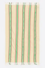 Toalla de playa de algodón, color beige claro, con diseño a rayas verticales en tonos verde, rosa y marrón. Las rayas verdes contienen el texto 'BIMBA Y LOLA' repetido verticalmente. Presenta flecos en los bordes cortos.