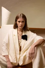 Saco de lino color negro, de corte amplio, con solapa, bolsillos falsos y pin de guitarra en la solapa.