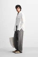 Sobrecamisa verde militar de lino, corte relaxed fit, con cuello solapa, manga larga con puños abotonados, bolsillos de parche con solapa en el pecho, aberturas laterales en el bajo y cierre frontal abotonado.