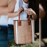Matera combinada en símil cuero color marrón y negro con textura croco. Tiene división interior, asas cortas de mano y broche en el asa.