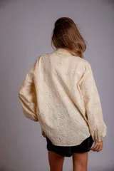 Camisa celeste con estampado de flores blancas, corte clásico, cuello camisero y mangas largas abullonadas.