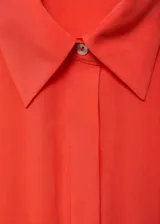 Vestido midi camisero color coral, de corte evasé, manga corta, cuello camisero, cierre frontal con botones y cinturón con hebilla.