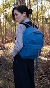 Mochila azul con detalles en cuero marrón, bolsillo frontal con cierre, bolsillos laterales con elástico, bolsillo trasero con cierre, correas acolchadas.