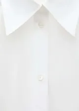 Camisa oversize blanca de popelina de algodón, con cuello camisero, manga larga con puños abotonados y cierre frontal con botones.