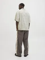 Camisa de manga corta con cuello resort y calce amplio, confeccionada en mezcla de viscosa y lino. Presenta un estampado integral de motivos marinos y botánicos en tonos beige y crema, con cierre frontal de botones.