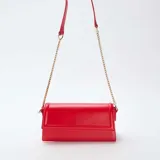 Bolso tipo sobre color rojo, con correa de cadena dorada.