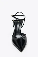 Zapato de tacón destalonado color negro charol, con tira trasera con hebilla y cierre con doble tira ajustable al tobillo.