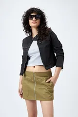 Minifalda color verde militar de corte recto con cierre metálico frontal visible, bolsillos laterales y tachas decorativas.