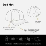 Gorra negra de poliéster reciclado, estilo dad hat, con bordado de margarita blanca y nombre de la marca en verde.