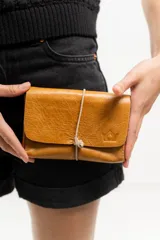 Billetera tipo sobre de cuero negro con cierre de elástico, separaciones internas y bolsillo con cierre para monedas.