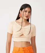 Blusa cropped color crema de viscosa con manga corta, escote en V, fruncido en el busto y abertura en el abdomen.