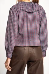 Camisa a cuadros azul y rosa con cuello babero, mangas largas abullonadas y cierre frontal con botones.