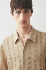 Camisa de manga corta color beige en punto jacquard. Modelo con cuello inglés, tapeta clásica y bajo recto.