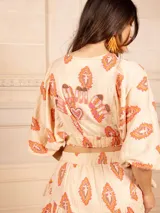 Top corto color crema con estampado de cachemir en tonos naranja y rosa, escote elástico con volantes, mangas cortas abullonadas y corte crop.