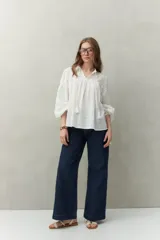 Blusa blanca de algodón con encaje floral en la parte superior, mangas largas abullonadas y escote con lazo.