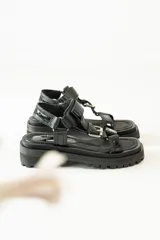 Sandalias con plataforma color marrón, con tiras de cuero color blanco y marrón con hebillas metálicas.