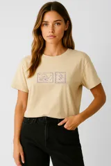 Remera color beige con estampado de sellos con motivos de jardinería. De corte recto, cuello redondo y mangas cortas.
