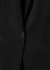 Blazer negro entallado con solapas de muesca, hombros estructurados, abertura posterior y dos bolsillos de ribete delanteros.