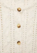Cárdigan color crema de tejido de punto grueso con diseño trenzado y calado. Tiene cuello redondo, cierre frontal con botones y mangas largas.