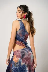 Conjunto de falda larga y top asimétrico con estampado tie-dye en tonos azul, naranja y marrón. El top es de un solo hombro y tiene un collarín con flecos dorados.