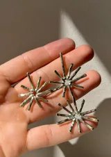 Par de aros colgantes de metal dorado con forma de sol. Cada aro tiene dos soles, uno más pequeño arriba y otro más grande abajo.