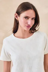 Remera blanca de manga corta con cuello redondo y bordados florales monocromáticos en relieve.