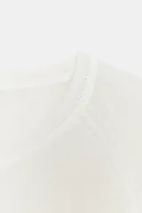 Jersey de punto liso, color azul brillante, con cuello redondo y manga larga. Presenta acabados en rib en puños, cuello y bajo, con aberturas laterales en el ruedo.