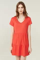 Vestido corto lila con cuello en V y mangas cortas. Tiene corte holgado y dos volados en la falda.
