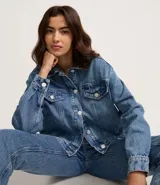 Campera boxy de jeans azul, con cuello clásico, cierre frontal con botones, bolsillos con solapas abotonadas en el pecho y recortes.