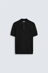 Polo negro de punto con cuello solapa, cierre frontal de botonadura, manga corta y acabados en rib.