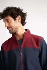 Campera polar para hombre, color azul marino con canesú y cuello en color borgoña. Tiene cierre frontal completo, bolsillos laterales con cierre, puños y ruedo elastizados, y logo estampado en el pecho.