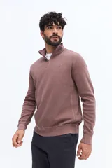 Buzo de algodón color verde musgo, con cuello alto y cierre frontal parcial. Presenta puños y cintura acanalados, y un pequeño logo bordado en el pecho.