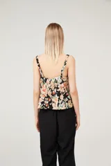 Musculosa con estampado floral multicolor sobre fondo negro, breteles anchos y escote cuadrado.