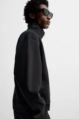 Sudadera negra de algodón con cuello alto y cierre de cremallera frontal. Corte relaxed fit, manga larga y terminaciones en rib.