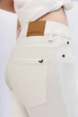 Pantalón jean blanco de tiro alto y calce skinny, con proceso de coating de acabado símil cuero. Pierna al cuerpo hasta el tobillo.