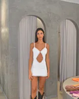 Minivestido blanco con breteles finos, escote en V con volados y abertura en el abdomen.