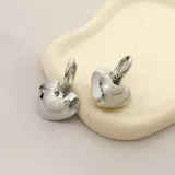 Par de aros plateados de acero quirúrgico hipoalergénico, con forma de corazón inflado.