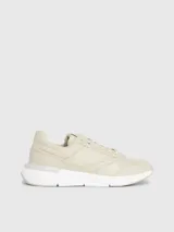Zapatillas urbanas color beige, confeccionadas en cuero y tela, con suela blanca y cordones. Presentan monograma de la marca en el lateral.