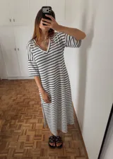 Vestido midi de punto con rayas horizontales blancas y negras, escote en V y mangas cortas. Presenta tajos laterales.