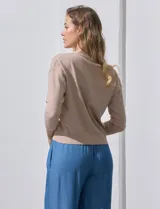 Cárdigan color beige tejido en hilado fino, con escote en V y cierre frontal con un botón.