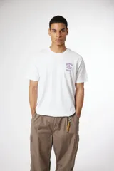 Remera blanca de manga corta con cuello redondo y un pequeño estampado frontal en tonos rosados y morados que incluye el texto "SUSHI & POW" y caracteres japoneses.