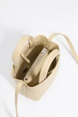 Bolso mini tipo tote de cuero color marrón claro, con doble asa corta, correa larga opcional y logo de la marca en el frente.